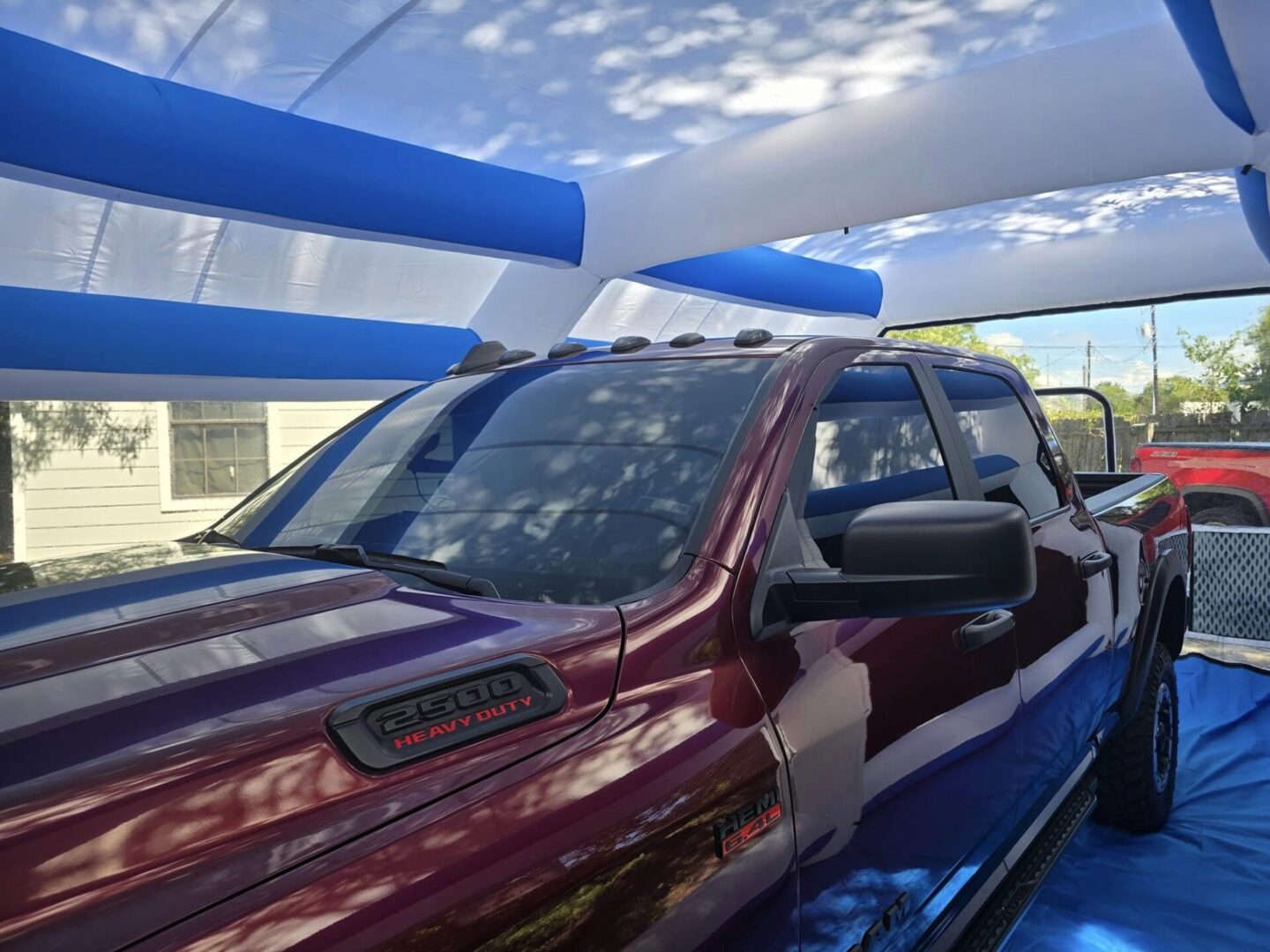 A red truck parked in front of blue and white tents.