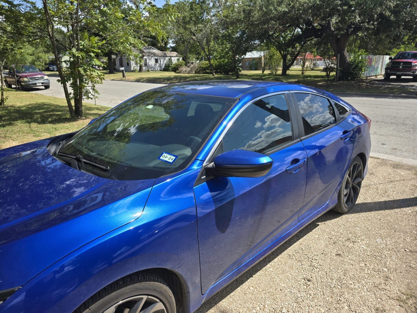 A blue car parked on the side of a road.