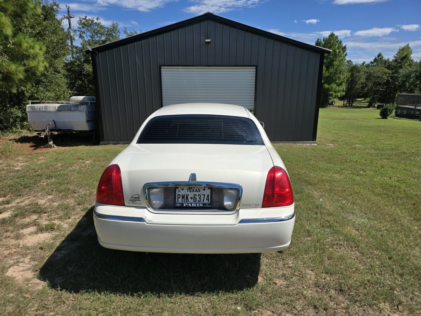 A white limo parked in front of a black garage.